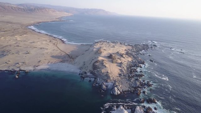 Las Tortolas beach aerial footage at Atacama Desert the sunset ray lights illuminate this amazing and idyllic beach in the middle of the desert, an arid awe landscape crashed by Pacific Ocean waters