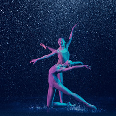 Two young female ballet dancers under water drops