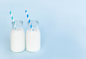 Bottle of fresh milk with straw on light blue background, food healthy concept