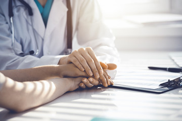 Doctor reassuring patient woman while sitting at the desk in clinic, just hands. Medicine and best service concept