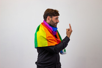 Portrait of handsome young man with gay pride movement LGBT Rainbow flag and brown hair covering...