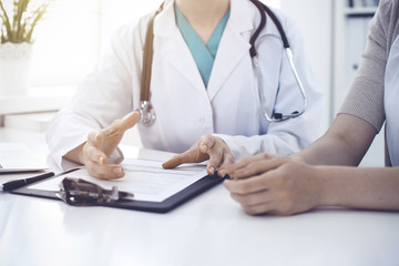 Doctor and patient are discussing something in clinic, just hands at the desk. Medicine and best service concept
