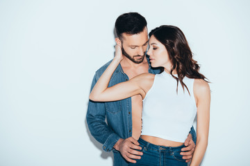 sensual loving couple in jeans embracing on grey