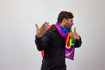 Portrait of handsome young man with gay pride movement LGBT Rainbow flag and brown hair giving a...