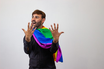 Portrait of handsome young man with gay pride movement LGBT Rainbow flag and brown hair pointing...