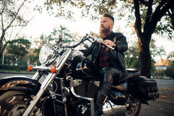 Fototapeta na wymiar Biker sitting on a motorcycle leaning on a helmet