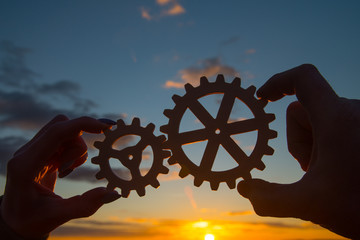 hands of businessmen assemble gears into a puzzle mechanism. Business concept idea, cooperation, teamwork, innovation, creativity. strategy, friendship.