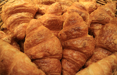 Heap of fresh baked mouthwatering almond croissant pastries in the bakery shop