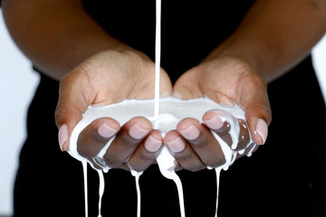 Black African hands cupped holding milk, pouring into hands for beauty industry