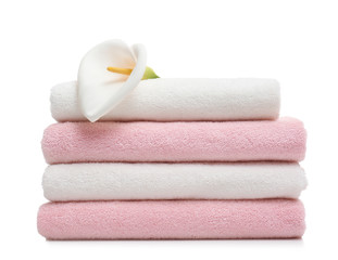 Stack of clean folded towels with flower on white background