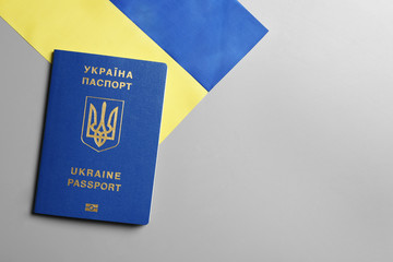 Ukrainian travel passport and national flag on grey background, top view with space for text. International relationships