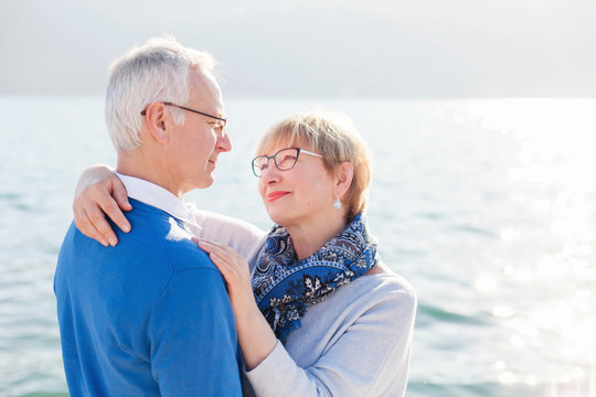 Happy senior couple at sea beach outdoor. Man and woman are hugging, embracing, enjoying retirement and life. Concept of wellbeing, happiness, male and female health, lifestyle moments.