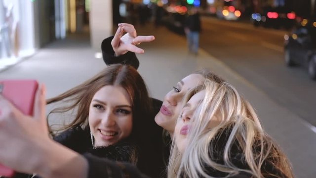 Girls night out party. Beautiful female friends having fun, taking selfie on the street with blur city lights.