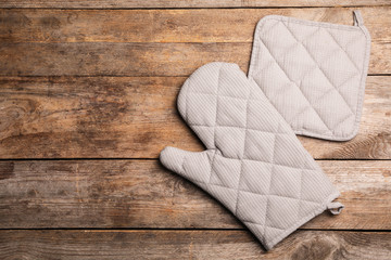 Protective oven glove and potholder on wooden table, top view with space for text