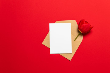 Letter, envelope in eco paper and red tulip on background. Valentine