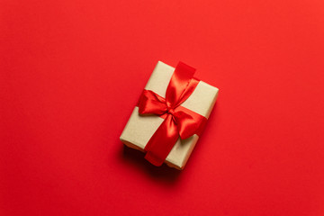 brown gift box with red bow on red table, top view