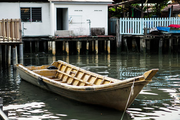 Floating wooden boat next to a floating village in Malaysia.Old wooden boat used for fishing by villagers, close-up