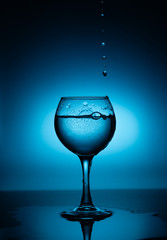 Wine glass with flowing white wine (water) on a blue gradient background