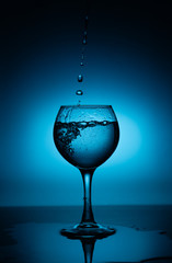 Wine glass with flowing white wine (water) on a blue gradient background