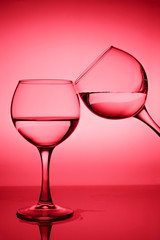 Wine glasses with white wine (water) on a red gradient background