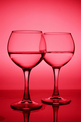 Wine glasses with white wine (water) on a red gradient background