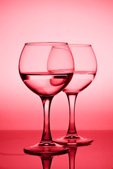 Wine glasses with white wine (water) on a red gradient background
