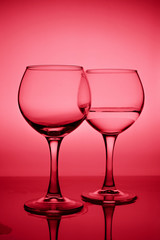 Wine glasses with white wine (water) on a red gradient background