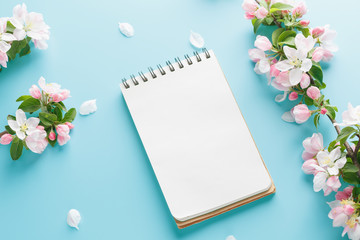 Blooming spring sakura on a blue background with notepad space for a greeting message. The concept of spring and mother's day. Beautiful delicate pink cherry flowers in springtime