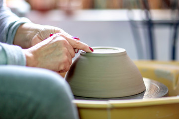 Artist make pot of mug at pottery wheel with hands