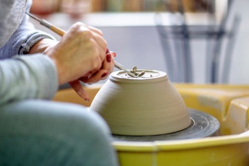 Fototapeta na wymiar Artist make pot of mug at pottery wheel with hands