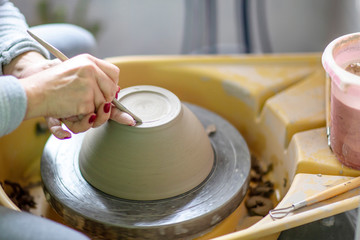 Artist make pot of mug at pottery wheel with hands