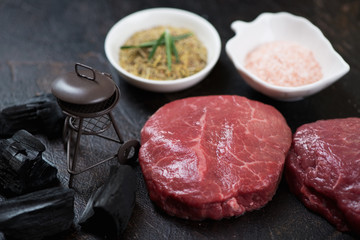 Close-up of fresh uncooked marbled beefsteaks with decorative grill and seasonings, studio shot