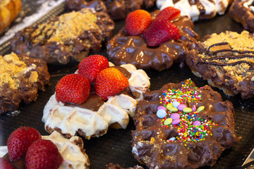 Waffles with whipped cream, strawberries, chocolate and candies