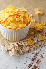 Bowl with golden flakes on a linen, on a light wooden table, next to a spoon. Rustic country style. View from above