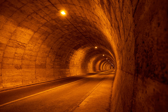 Carretera que pasa por tunel con alumbrado rojizo 