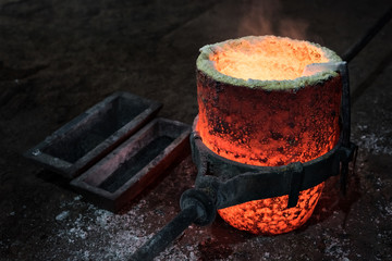 Crisol con bronce fundido recién sacado del horno