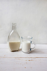 Delicious fresh milk on a white wooden background. A bottle of milk and a glass of milk. copy space