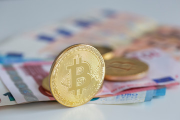 Bitcoins on first plan as virtual banknotes with real money on the desk