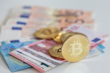 Bitcoins on first plan as virtual banknotes with real money on the desk