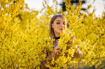 Blonde in spring in flowering trees and bushes
