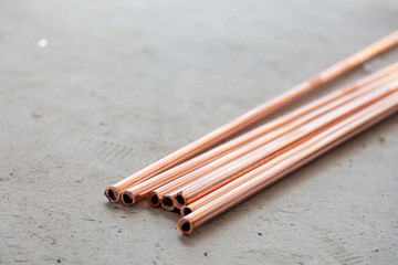 Close-up many new copper dyne pipes on the concrete floor. Concept installation, replacement of plumbing, repair of the pipeline, professional master plumber, leakage pipe