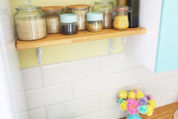 Kitchen shelf with cans of products. View from above. A bouquet of flowers on the tabletop...