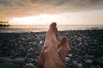 Legs of man on the beach at sunset in sea