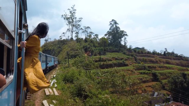 Woman enjoying train ride through Sri Lanka tea plantations