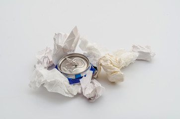 Crushed compressed aluminum can of a carbonated drink with crumpled sheets of paper. Pollution, waste, ecology