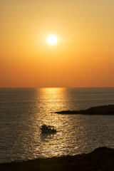 Beautiful sunset on the Adriatic Sea, a small boat swinging in the solar path