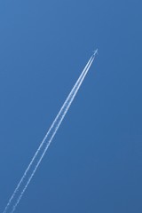 France - Plane flying and leaving a long white trail behind in the blue sky
