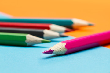 L&aacute;pices de colores para pintar y dibujar sobre fondo liso celeste. Vista de cerca y de frente