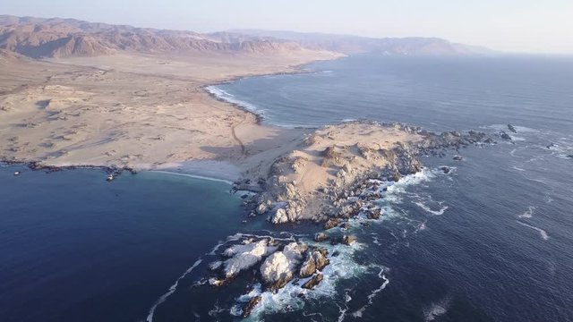 Las Tortolas beach aerial footage at Atacama Desert the sunset ray lights illuminate this amazing and idyllic beach in the middle of the desert, an arid awe landscape crashed by Pacific Ocean waters
