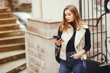 Beautiful girl in a city. Woman with phone. Girl at the fence